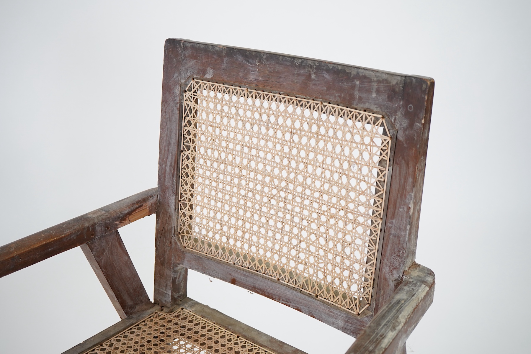 Manner of Pierre Jeanneret (Swiss, 1896-1967): A solid teak and braided canework armchair